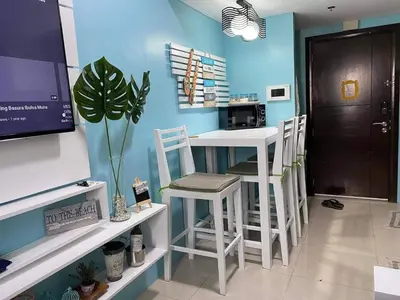 a kitchen with a bar with stools in a room at One Palm Tree Villas Near NAIA3 in Manila