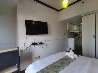 a bedroom with a bed with a flat screen tv on the wall at citadel inn apartment in Manila