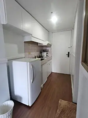 a small kitchen with a white refrigerator in a room at citadel inn apartment in Manila