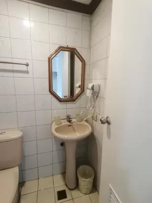 a bathroom with a sink and a mirror and a toilet at citadel inn apartment in Manila