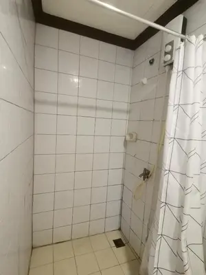 a white tiled shower with a shower curtain in a bathroom at citadel inn apartment in Manila