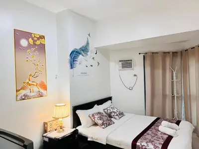 a bedroom with a bed and a table with a lamp at Dreamy Sunset Bay in Manila