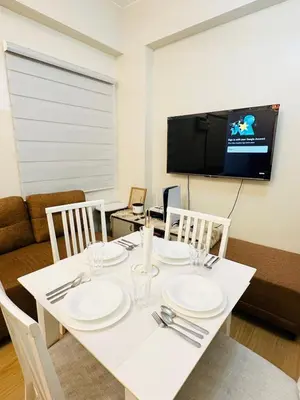 a dining room with a white table with chairs and a tv at Starlight Suites in Trece Martires