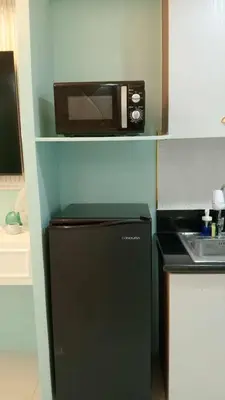 a small kitchen with a microwave on top of a refrigerator at Homefort at Shore Residences in Manila