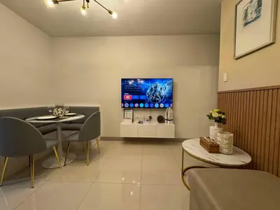 a living room with a table and a tv on the wall at Homefort at S Residences in Manila