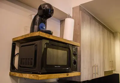 a microwave sitting on top of a wooden cabinet at RQ Cozy One Bedroom Condo, Coast Residences Pasay in Manila