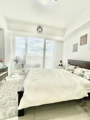 a bedroom with a large bed and a clock on the wall at A3J Staycation at Azure Urban Resort Residences in Manila