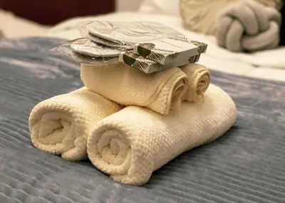 a folded towel with a pile of toiletries on a bed at Cozy & Airy Suite near Venice Mall FREE Pool & Gym in Manila