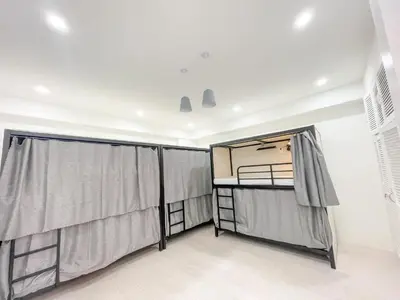 a room with two beds and curtains in it at Travelers Inn - Modern Capsule Bunks, Makati in Manila