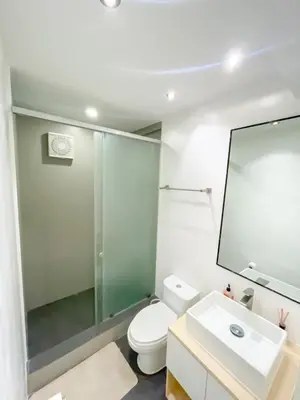 a bathroom with a toilet and a sink and a mirror at Travelers Inn - Modern Capsule Bunks, Makati in Manila