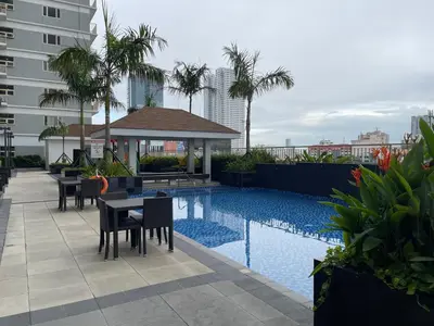 a swimming pool with tables and chairs next to a building at SMDC Coast Residences in Manila