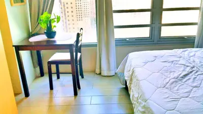 a bedroom with a table and a chair and a window at Studio-Type Condo at Eastwood Legrand 3 in Manila