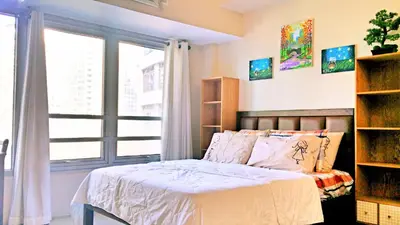 a bedroom with a bed and a large window at Studio-Type Condo at Eastwood Legrand 3 in Manila
