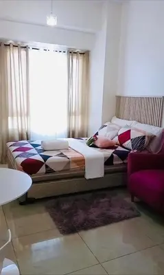 a bedroom with a bed with pillows and a window at The Beacon Makati in Manila