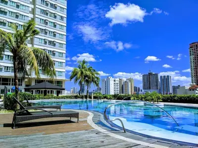 a large swimming pool with palm trees and buildings at The Beacon Makati in Manila