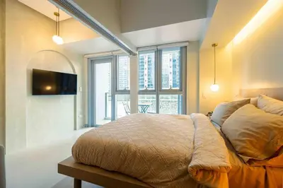 a bedroom with a large bed with a tv on the wall at 1 BR with balcony in Uptown BGC in Manila