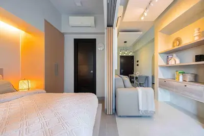 a bedroom with a bed and a table in it at 1 BR with balcony in Uptown BGC in Manila