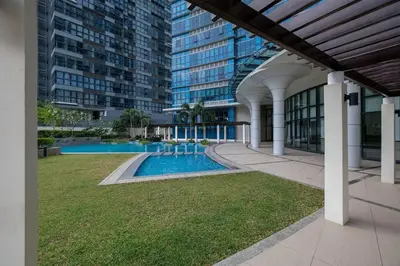 a large building with a swimming pool in a yard at Cozy 1BR with Balcony and Netflix in Uptown BGC in Manila