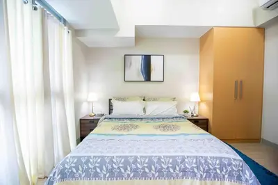 a bedroom with a bed with two lamps and curtains at Cozy 1BR with Balcony and Netflix in Uptown BGC in Manila