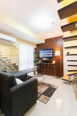 a living room with a couch and a television at A2J BGC Luxury 2BR Loft Near High Street, Airport in Manila