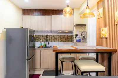 a kitchen with a bar with stools and a refrigerator at A2J BGC Luxury 2BR Loft Near High Street, Airport in Manila