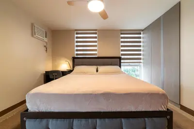 a bedroom with a large bed and a window at Luxury Condo at Venice Mall near Airport, BGC & Makati in Manila
