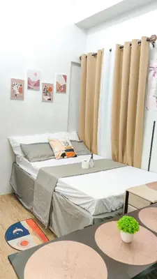 two beds in a room with curtains and tables at Anuva Stays in Manila