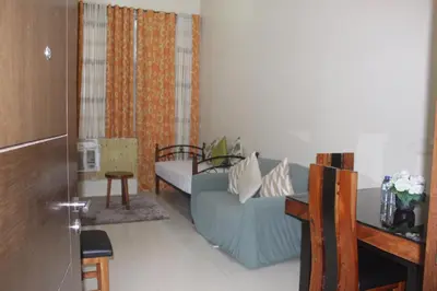 a living room with a blue couch and a table at Condo 1 Palm Tree Across NAIA T3 in Manila