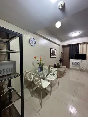 a living room with a table and chairs and a clock at Condo 1 Palm Tree Across NAIA T3 in Manila