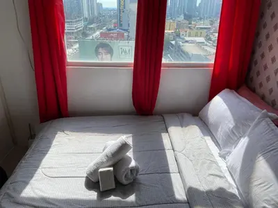 a bed in a room with a window with red curtains at Pierrecondotel in Manila