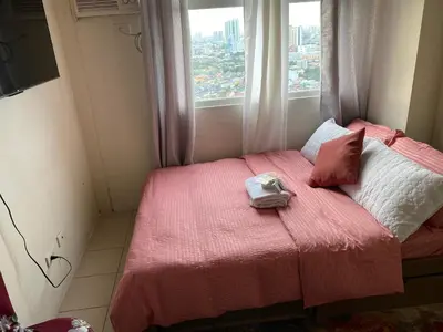 a small bedroom with a pink bed with a window at Pierrecondotel in Manila