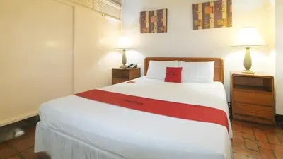 a bedroom with a large white bed with two lamps at RedDoorz at Broadway Court Apartelle II Quezon City in Manila