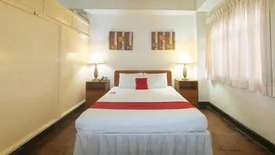 a bedroom with a large white bed with two lamps at RedDoorz at Broadway Court Apartelle II Quezon City in Manila