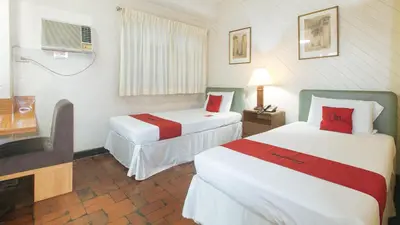 a hotel room with two beds and a television at RedDoorz at Broadway Court Apartelle II Quezon City in Manila