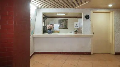 a lobby with a mirror and a counter with a vase of flowers at RedDoorz at Broadway Court Apartelle II Quezon City in Manila