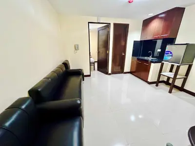a living room with a black couch and a kitchen at OYO 1045 Rayjan Apartelle in Manila