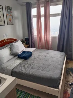 a bed sitting in a bedroom with a window at Nicecondotel in Manila