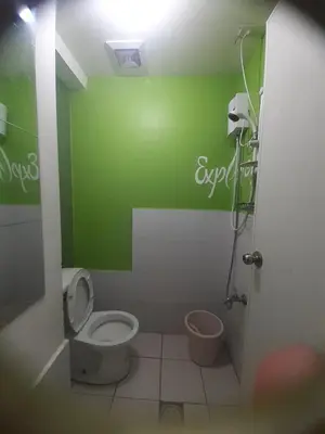 a bathroom with a toilet and a green wall at Nicecondotel in Manila
