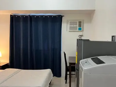 a room with a bed and a blue curtain at Dreamy Sunset Bay in Manila