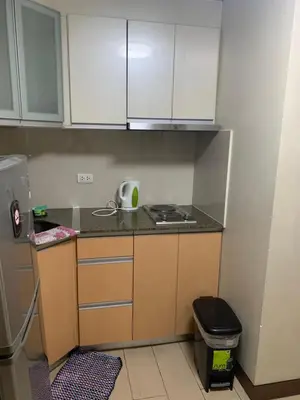 a small kitchen with white cabinets and a stove at RAMCONDOTEL in Manila