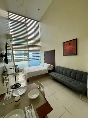 a living room with a couch and a bed at Cozy High Ceiling Studio @ Ortigas near Podium, Megamall in Manila