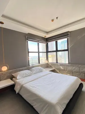a bedroom with a large white bed with two windows at Malate Bayview Mansion 17A/B in Manila