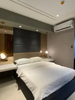 a bedroom with a large white bed with a black headboard at Malate Bayview Mansion 17A/B in Manila