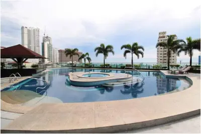 a large swimming pool with a boat in a city at Malate Bayview Mansion 17A/B in Manila