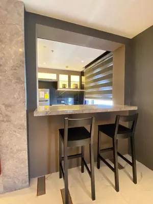 a kitchen with a bar with two stools around it at Malate Bayview Mansion 17A/B in Manila