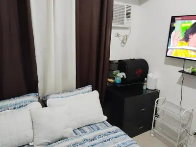 a living room with a bed and a flat screen tv at Pierrecondotel in Manila