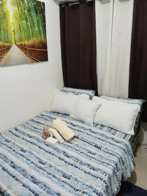 a bed with a blue and white blanket and pillows at Pierrecondotel in Manila