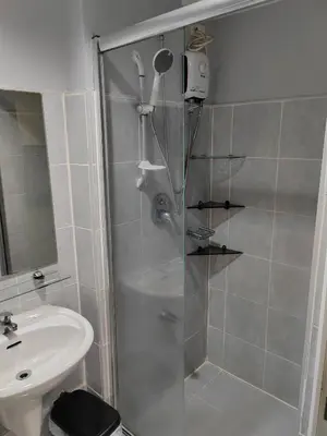a shower with a glass door next to a sink at Sea Residences-Reisha in Manila
