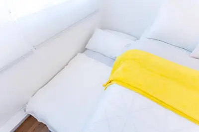 a white room with a bed with a yellow blanket at A2J Luxury 3BR BGC Loft Near Malls and Airport in Manila