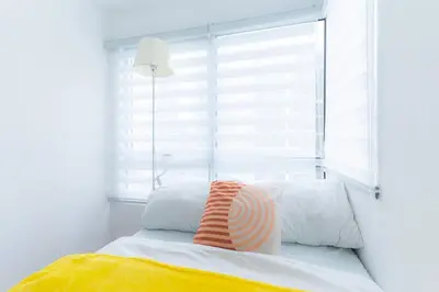 a bed with a window with an orange and white pillow at A2J Luxury 3BR BGC Loft Near Malls and Airport in Manila